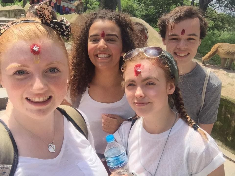 Hollie and other students posing for a selfie with traditional forehead markings.