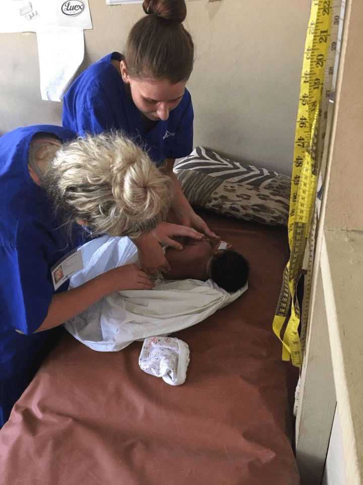 Courtney and Emily checking a newborn at a medical facility.